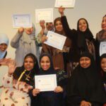 Group of Somali women, smiling and holding paper certificates.