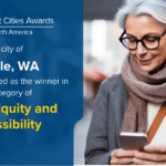 Image of a woman looking at phone. Text over blue background says: IDC Smart Cities Awards 2024 North America The City of Seattle, WA has been selected as the winner in the category of Digital Equity and Accessibility