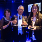 Two women and a man holding Emmy awards