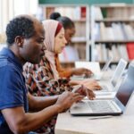 Three ethnically diverse individuals working on keyboards in a library