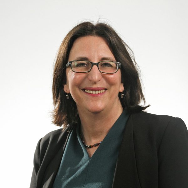 A smiling woman in a dark suit wearing glasses